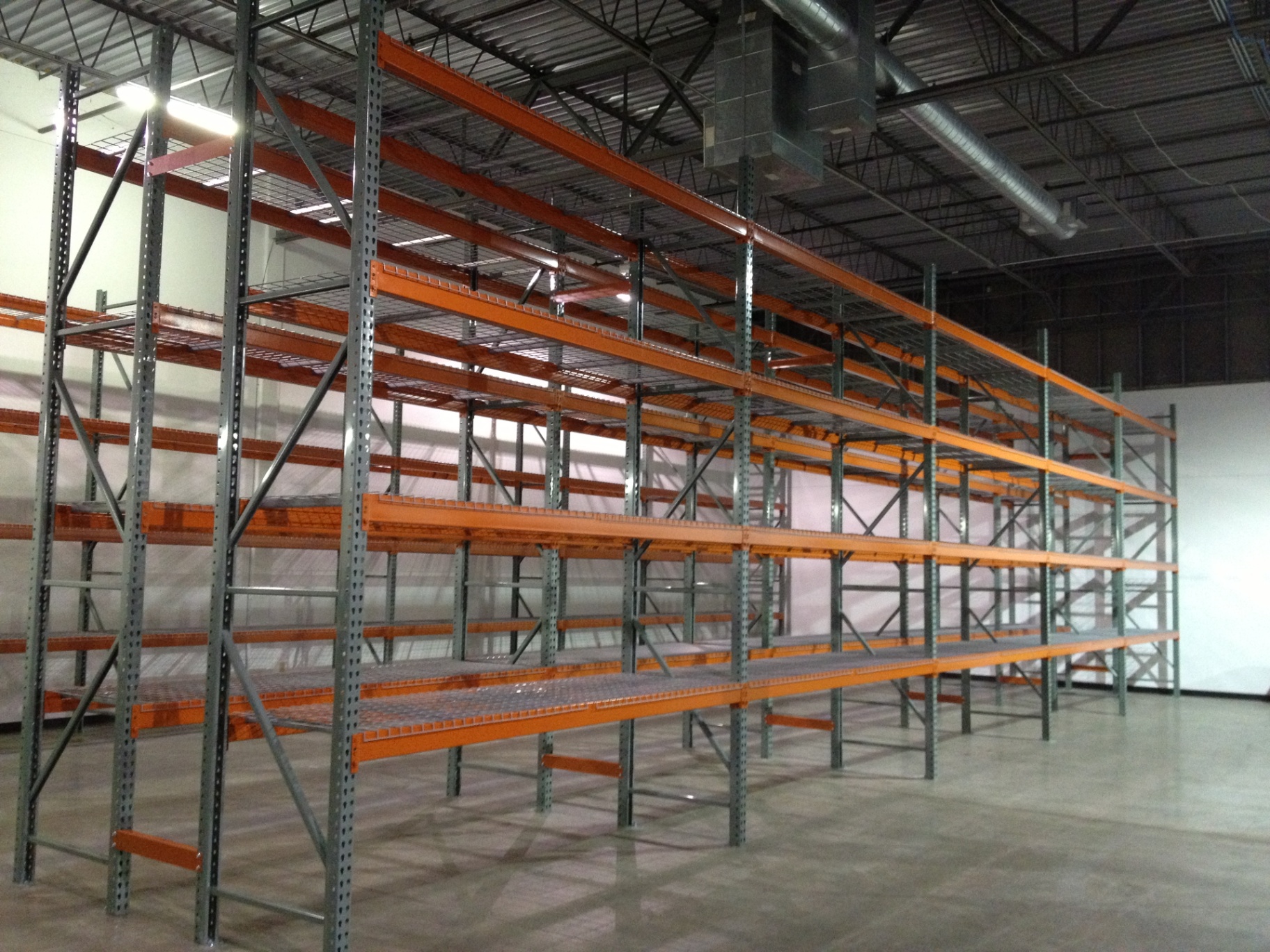 Selective pallet racking with grey uprights, orange beams, and wire decking