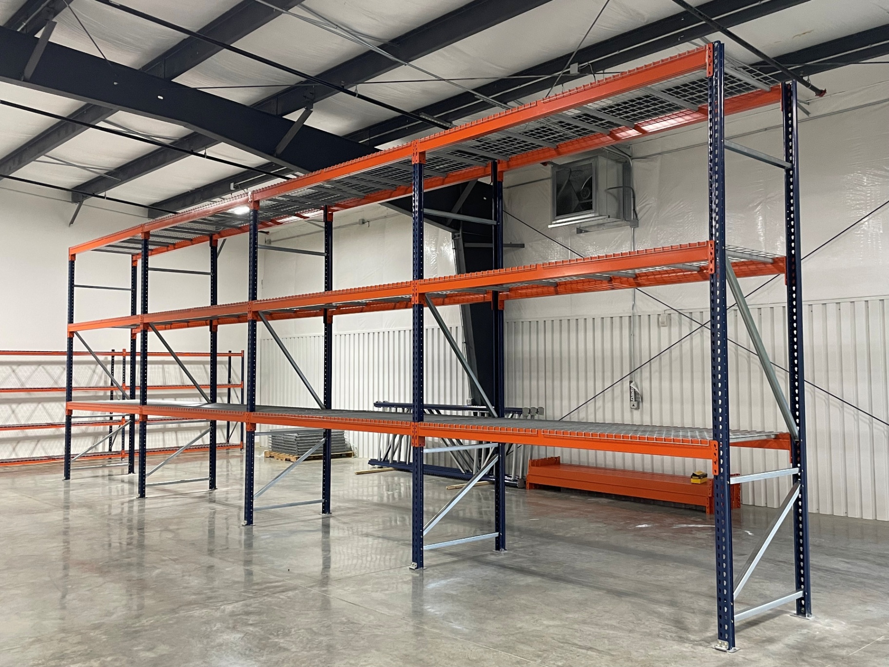 Selective pallet racking with orange beams, blue uprights, and wire decking in a warehouse