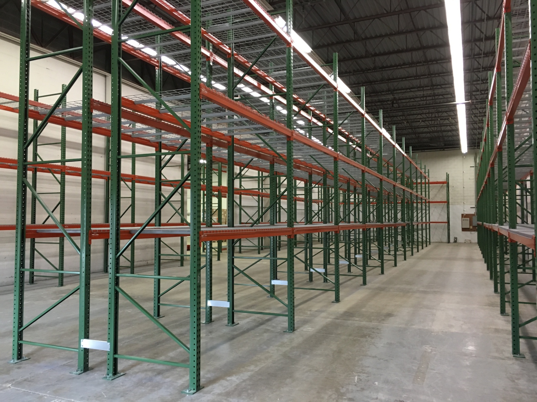 Long rows of selective pallet racking with green uprights and orange beams